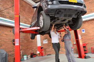 carro suspenso e mecanicos em baixo do carro